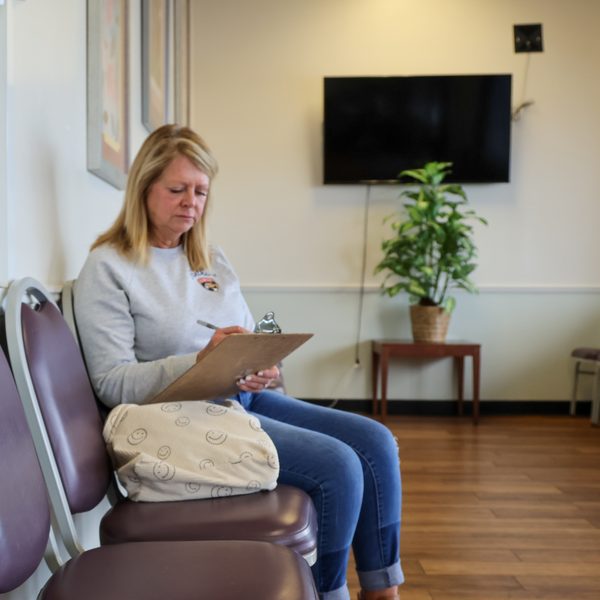 A patient filling in a form in the waiting room at the Pastor Paul Hoyer Health Center